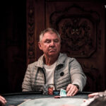 Ein Bild eines Pokertisches mit Spielkarten, Pokerchips und Getränken, aufgenommen während eines Pokerturniers.
