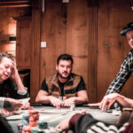 Ein buntes Pokerspiel mit Spielkarten, Jetons und Spielern, die um einen Tisch herum sitzen.