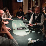 Ein professioneller Pokerspieler sitzt an einem Spieltisch, umgeben von Chips und Spielkarten. Er hat einen konzentrierten Ausdruck und scheint seine nächste Spielstrategie zu planen.