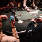 Ein professioneller Pokertisch mit grünem Filz, umgeben von Spielern, die Karten halten und Pokerchips stapeln.