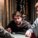 Ein Foto von einem Pokertisch mit Spielkarten, Pokerchips und Getränken, aufgenommen während eines Pokerturniers.