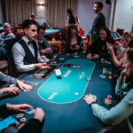 Ein Spieler mit Sonnenbrille und Kappe hält seine Pokerkarten in der Hand und wirft einen intensiven Blick auf den Pokertisch während eines Turniers.