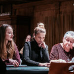 Ein Mann mit einer Kappe und einem blauen T-Shirt sitzt an einem Pokertisch mit Karten und Chips. Er hat eine ernsthafte Miene und scheint konzentriert zu sein.