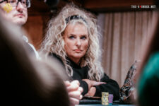 Ein professioneller Pokertisch mit grünem Filz, umgeben von Spielern mit Pokerchips und Karten in der Hand.