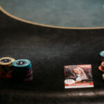 Ein Mann und eine Frau spielen Poker an einem Tisch in einem Casino. Der Mann hat Karten in der Hand und konzentriert sich auf das Spiel, während die Frau auf ihre Karten schaut. Die Szene ist in einem elegant