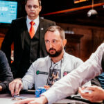 Ein Haufen von Pokerchips in verschiedenen Farben und Stapelhöhen auf einem grünen Pokertisch.