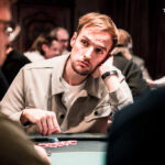 Ein Mann und eine Frau sitzen an einem Pokertisch und spielen Texas Hold'em. Der Mann hat gerade eine Hand gewonnen und lächelt triumphierend, während die Frau enttäuscht aussieht. Die Chips und K