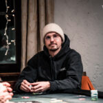 Ein stimmungsvolles Bild einer Pokerrunde mit vier Personen, die konzentriert an einem Tisch sitzen und Karten spielen. Die Spieler haben ernste Gesichtsausdrücke und halten ihre Karten ver