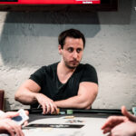 Ein professioneller Pokertisch mit grünem Filz, umgeben von Stühlen, Pokerchips und Spielkarten. Spieler sitzen um den Tisch herum und konzentrieren sich auf ihre Karten. Ein span