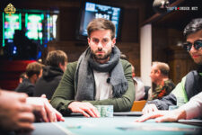 Ein Bild von vier Personen, die an einem Pokertisch sitzen und Karten spielen. Die Personen sind konzentriert und haben Pokerchips vor sich liegen. Ein Spieler hat gerade seine Karten aufgedeckt.