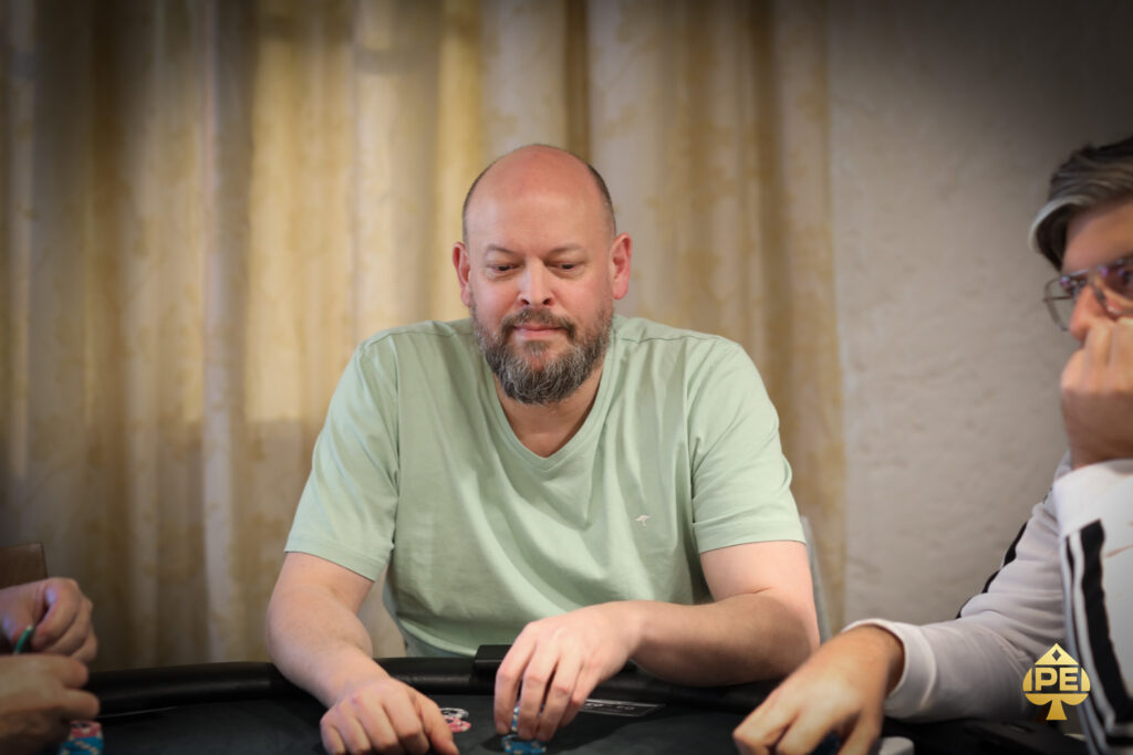 Ein Mann und eine Frau sitzen an einem Pokertisch und spielen Texas Hold'em. Der Mann hat gerade eine Hand ausgespielt und schaut gespannt auf die Karten der Frau. Die Frau hält ihre Karten vor sich