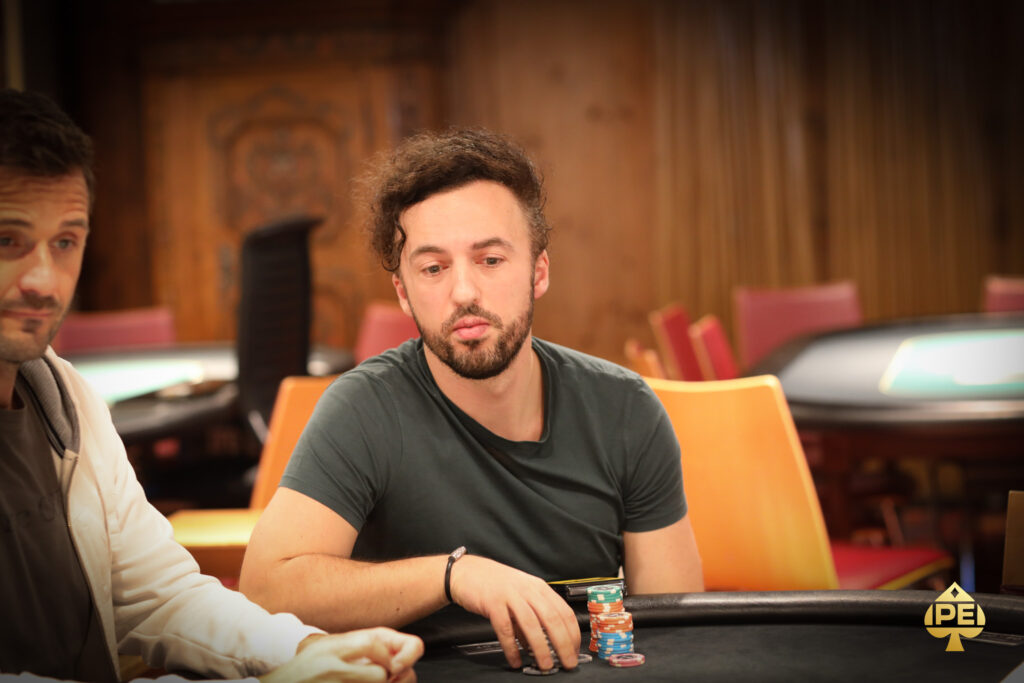 Ein Mann und eine Frau spielen Poker an einem eleganten Tisch in einem stilvollen Casino. Der Mann hat eine Hand mit Karten, während die Frau mit Konzentration ihre Karten betrachtet. Die Szene ist beleuchtet