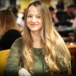Ein Mann und eine Frau sitzen an einem Pokertisch und spielen Poker. Der Mann hat gerade seine Karten aufgedeckt und schaut konzentriert auf seine Hand, während die Frau mit einem Pokerface reagiert. Die