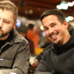 Ein Mann sitzt an einem Pokertisch, umgeben von Spielkarten und Jetons. Er hat eine ernste Miene und studiert konzentriert seine Karten.
