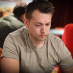 Ein Mann und eine Frau sitzen an einem Pokertisch und halten ihre Karten in der Hand. Sie scheinen konzentriert und ernsthaft in das Spiel vertieft zu sein. Im Hintergrund sind Pokerchips und