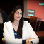 Ein Mann und eine Frau sitzen an einem Pokertisch und spielen Karten. Der Mann hält seine Karten verdeckt, während die Frau mit einem nachdenklichen Gesichtsausdruck auf ihre Karten schaut.