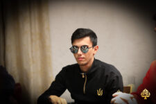 Ein Mann und eine Frau sitzen an einem Pokertisch und spielen Karten. Der Mann hat einen Anzug an, die Frau trägt ein elegantes Abendkleid. Sie schauen konzentriert auf ihre Karten. Im