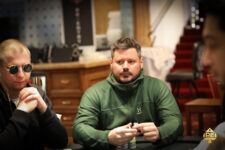 Ein Mann und eine Frau spielen Poker am Tisch in einem eleganten Casino. Der Mann hat eine Hand mit Spielkarten, während die Frau konzentriert ihre Karten betrachtet. Ein Stapel Jetons liegt vor ihnen auf dem