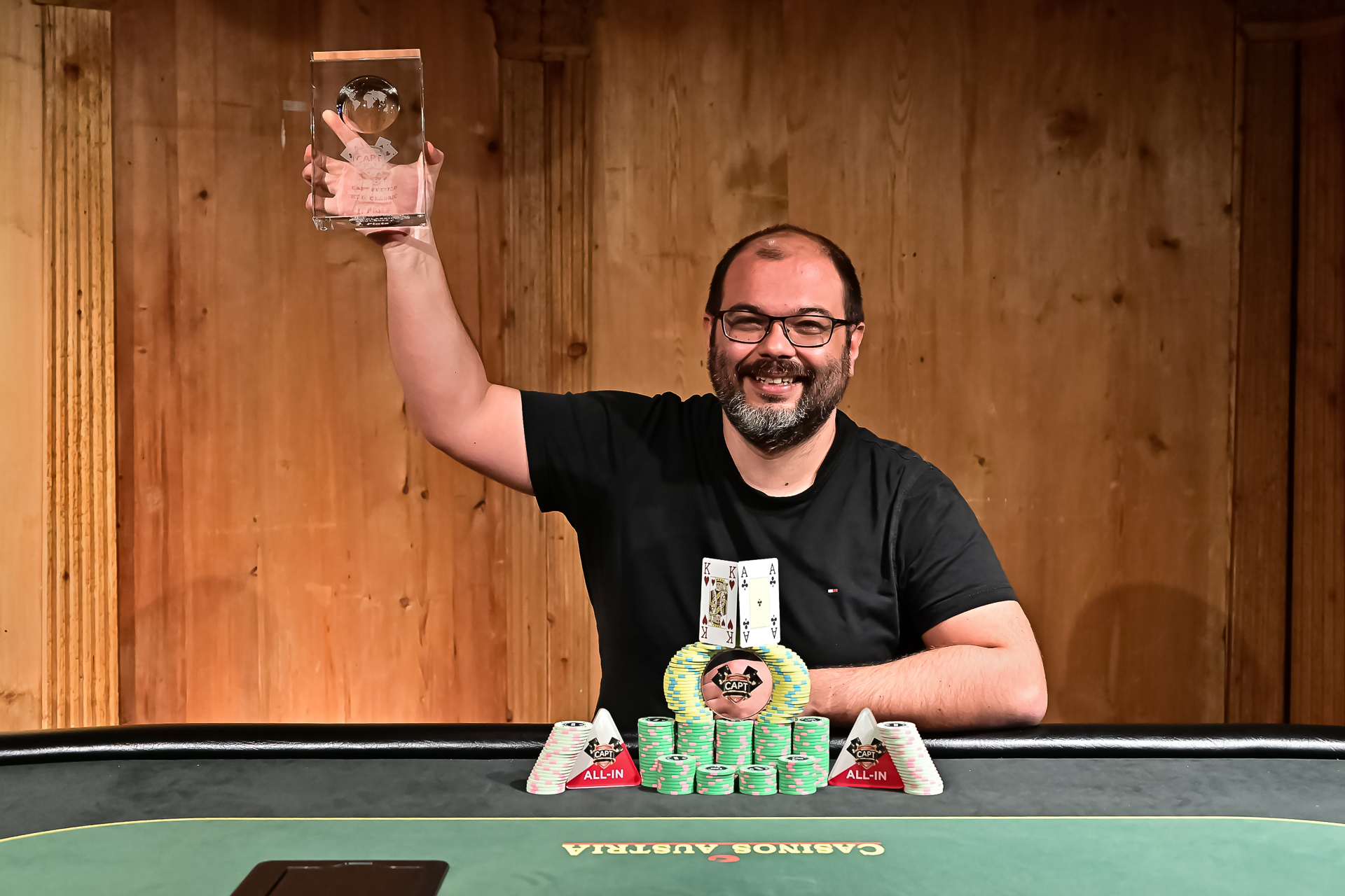 Ein Pokerspieler sitzt an einem Tisch bei einem Turnier in Seefeld. Er hält seine Karten in der Hand und betrachtet konzentriert den Spielverlauf. Die Atmosphäre ist gespannt