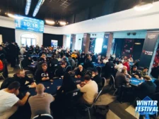 Ein Foto eines gut beleuchteten Pokerraums mit vielen Tischen, an denen Spieler sitzen und Karten spielen. Die Atmosphäre ist lebhaft und gesellig, mit einem Mix aus Spannung und Konzentration in der Luft