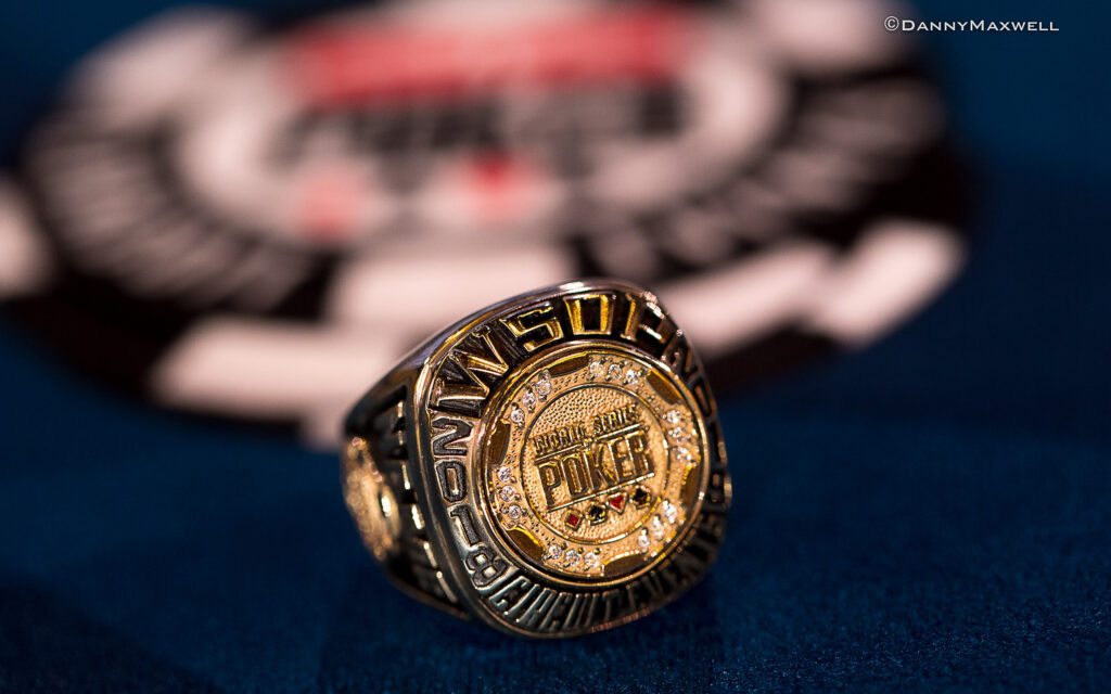 Ein goldener WSOP Circuit Ring mit Diamanten und dem WSOPC-Logo auf einem schwarzen Hintergrund.