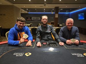 Ein Mann und eine Frau spielen eine Partie Poker. Der Mann hat eine Hand voll Karten und schaut konzentriert auf den Tisch, während die Frau mit einem selbstbewussten Lächeln ihre Karten betrachtet.