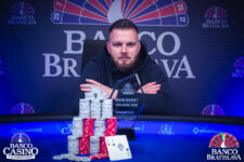 Ein glücklicher Pokerspieler feiert seinen Sieg mit einem breiten Lächeln und einer Hand voll Spielkarten in der Luft.