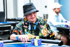 Ein Mann sitzt an einem Pokertisch, umgeben von Chips und Karten. Er trägt eine Brille und konzentriert sich auf sein Blatt.
