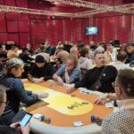 Ein Stapel grüner Pokerchips auf einem Tisch mit Spielkarten und einem Dealer-Button.