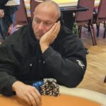 Ein Mann und eine Frau sitzen an einem Pokertisch und spielen eine Partie Poker. Der Mann hat gerade seine Karten angeschaut und scheint nachzudenken, während die Frau mit einem selbstbewussten Blick auf ihre K