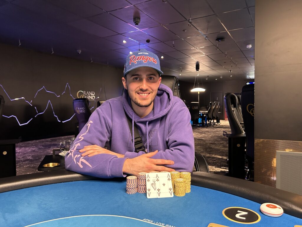 Ein glücklicher Pokerspieler feiert seinen Sieg mit einer Hand voll Chips und einem breiten Lächeln auf dem Gesicht.