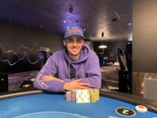 Ein glücklicher Pokerspieler feiert seinen Sieg mit einer Hand voll Chips und einem breiten Lächeln auf dem Gesicht.