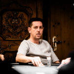 Ein Stapel bunter Pokerchips auf einem grünen Pokertisch mit Karten und Spielmarken.