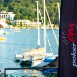 Ein professioneller Pokertisch mit grünen Filz, umgeben von Spielkarten, Pokerchips und einem Dealer-Button. Spieler sitzen an dem Tisch und konzentrieren sich auf ihre Karten.
