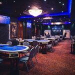 Ein glücklicher Mann sitzt an einem Pokertisch und hält zwei Asse in seiner Hand. Andere Spieler sind im Hintergrund zu sehen.