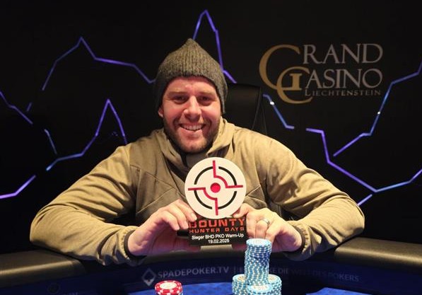 Ein professioneller Pokertisch mit grüner Filzoberfläche, umgeben von roten gepolsterten Stühlen. Auf dem Tisch liegen Spielkarten, Pokerchips und Getränke. Spieler mit