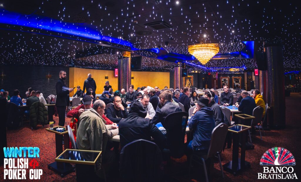 Ein Panoramablick auf eine große Pokertischrunde während des Day 1 der AWP Poker Championship. Die Spieler sitzen konzentriert an ihren Plätzen und platzieren ihre Einsätze. Die Atmosphäre ist