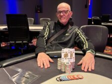 Ein glücklicher Pokerspieler jubelt und hält eine große Trophäe in die Luft nach seinem Sieg bei einem Saturday Deepstack Freezout-Turnier.