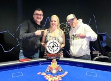 Ein professioneller Pokertisch mit Spielkarten, Pokerchips und Getränken. Vier Personen sitzen um den Tisch herum und konzentrieren sich auf ihre Karten.