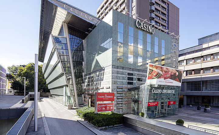 Ein elegantes Innendesign eines Casinos mit stilvollen Möbeln, Kronleuchtern und einer Bar, die eine luxuriöse Atmosphäre ausstrahlt. Menschen in schicker Kleidung sind zu sehen, wie