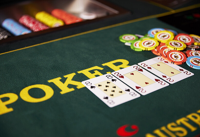 Ein Pokertisch mit Spielkarten und Chips, auf dem der Flop offenliegt und ein großer Pot in der Mitte steht.