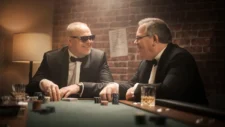 Stefan Raab und Elton sitzen bei RTL an einem Pokertisch. Stefan Raab hat eine Pokerkarte in der Hand und Elton schaut konzentriert auf seine Karten.