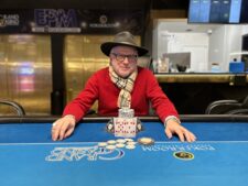 Ein glücklicher Pokerspieler mit einer Siegerprämie in Form von Bargeld und Trophäen.