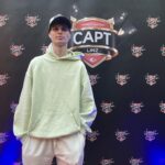 Ein Mann und eine Frau sitzen an einem Pokertisch, der Mann hält Karten in der Hand, während die Frau intensiv auf ihre Karten schaut. Hinter ihnen sind Pokerchips und Getränke zu sehen.