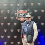 Ein Mann und eine Frau sitzen an einem Pokertisch, sie haben Karten in der Hand und schauen konzentriert auf den Tisch. In der Mitte des Tisches liegen Pokerchips und Karten. Die Atmos