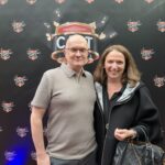 Ein kunstvoll gestalteter Pokertisch mit grünem Filz, umgeben von Spielkarten, Pokerchips und Getränken. Menschen sitzen um den Tisch und konzentrieren sich auf das Spiel