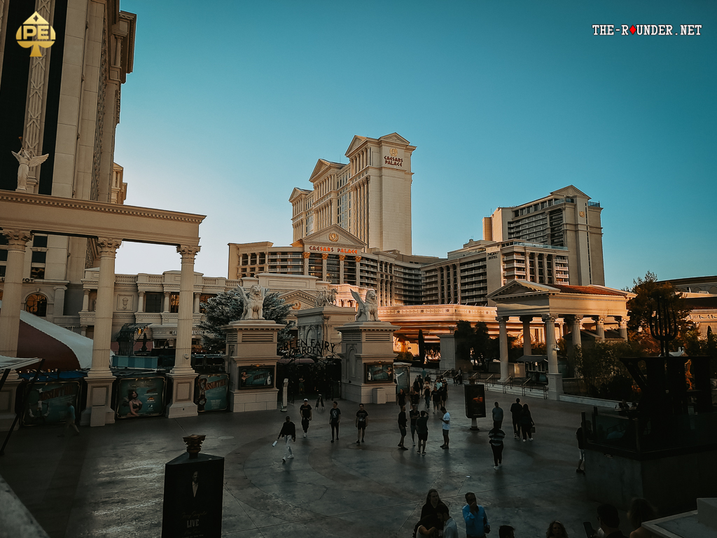 Ein beleuchtetes Bild des Caesars Palace Hotels in Las Vegas bei Nacht mit dem berühmten Wahrzeichen der römischen Säulen und Statuen.