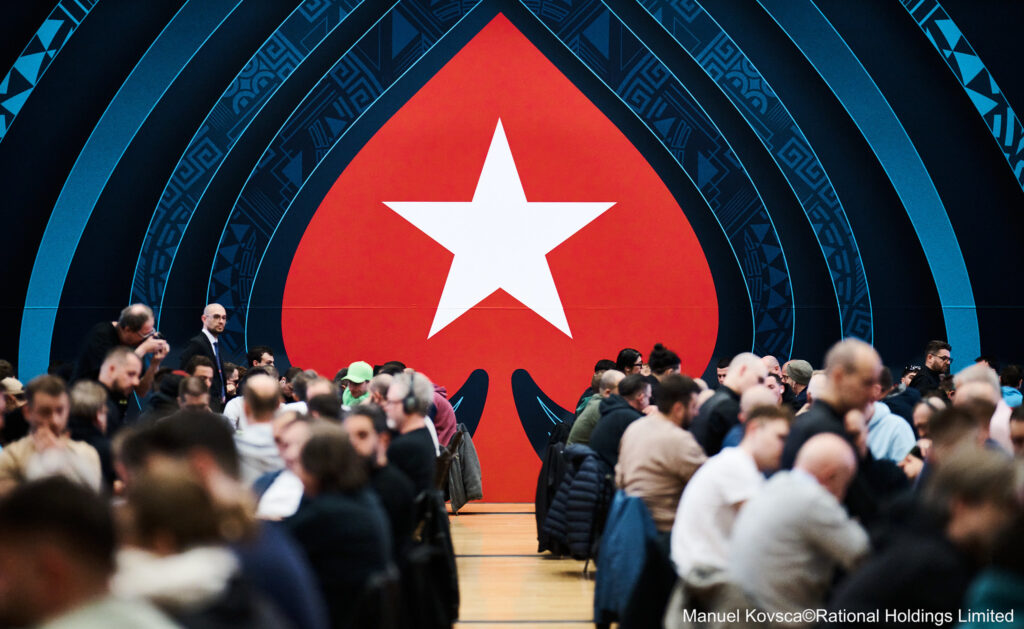 Ein bunter Haufen von Pokerchips in verschiedenen Farben und Werten, die auf einem Tisch gestapelt sind. Einige Chips sind lose verstreut und funkeln im Licht. Ein Dealer-Button liegt in der Mitte
