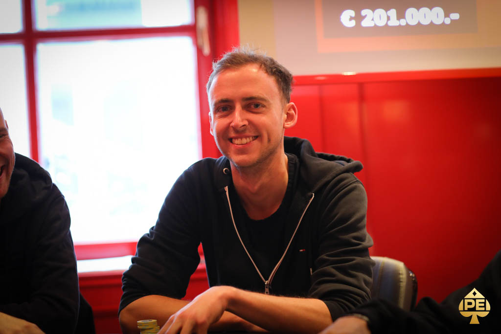 Ein Mann sitzt an einem Pokertisch und schaut konzentriert auf seine Karten.