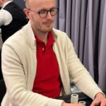 Ein Gruppenfoto von Pokerspielern, die an einem Tisch sitzen und Karten spielen.